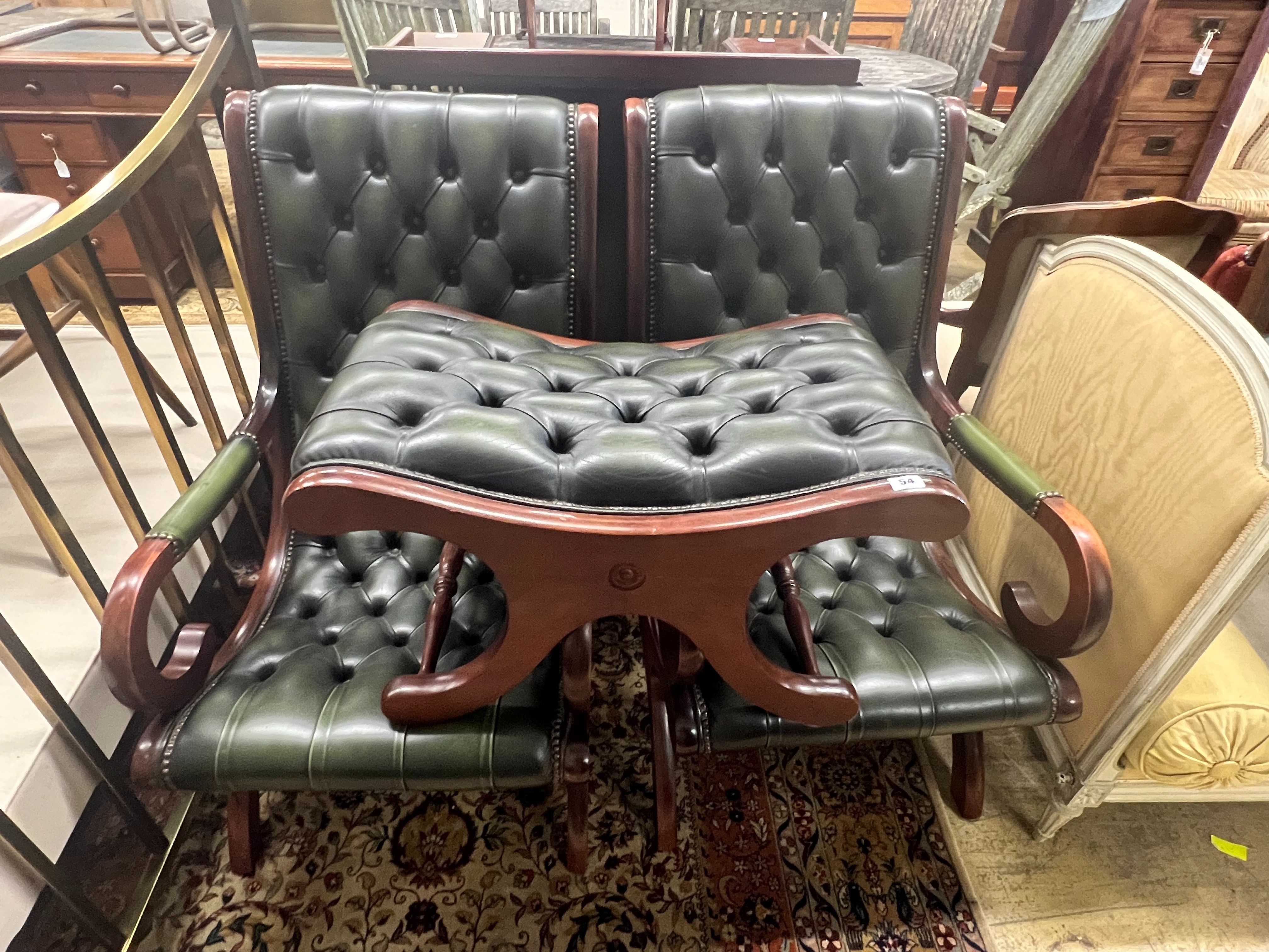 A pair of Victorian style mahogany and buttoned green leather open armchairs and matching footstool